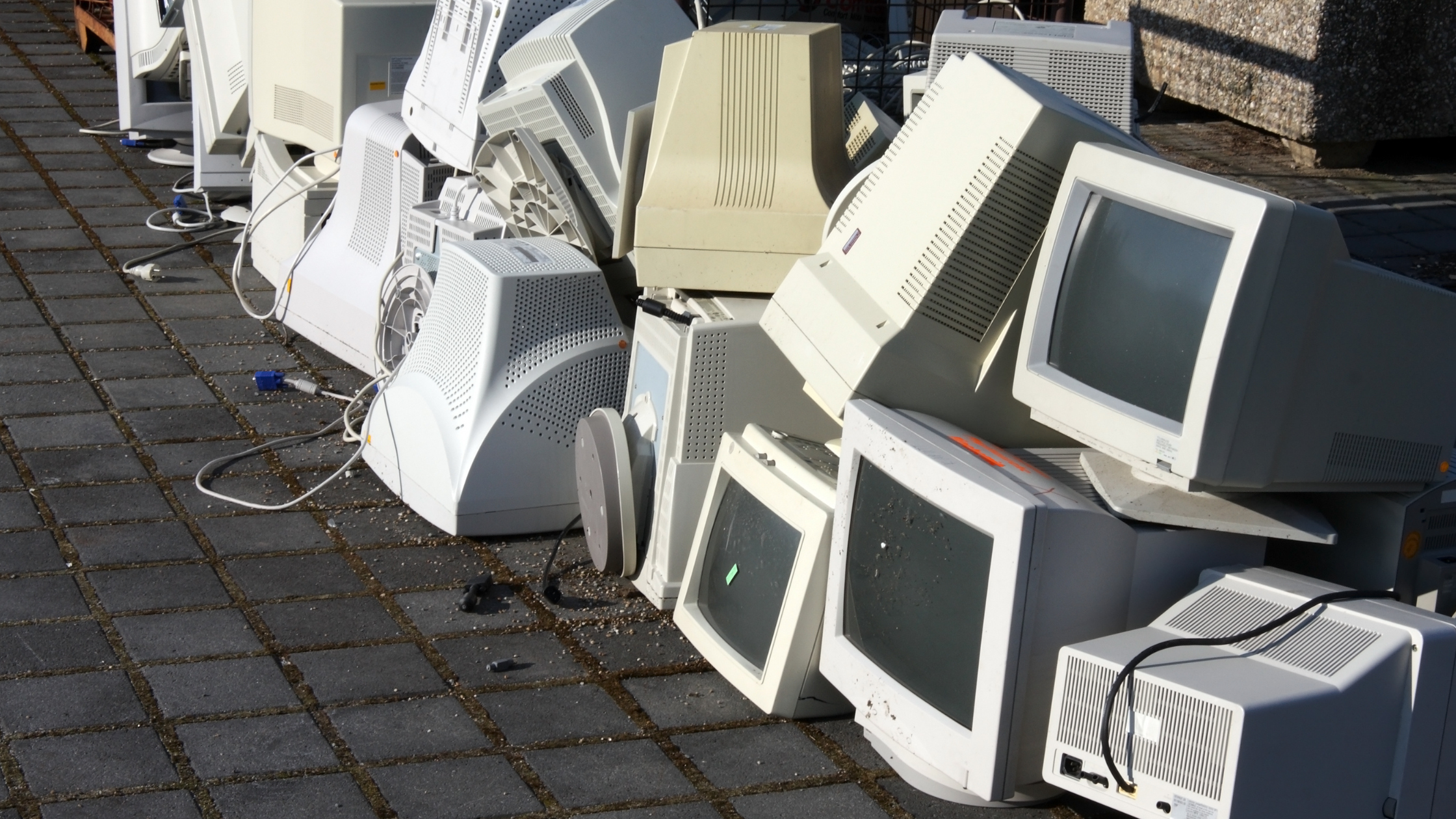 pile of outdated computer hardware outside in the sun, communicating a build up of technical debt